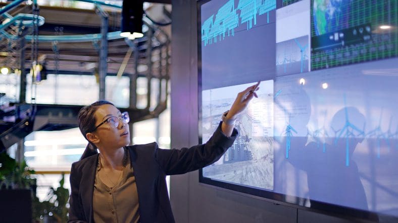 Engineer pointing at touchscreen displaying renewable energy data