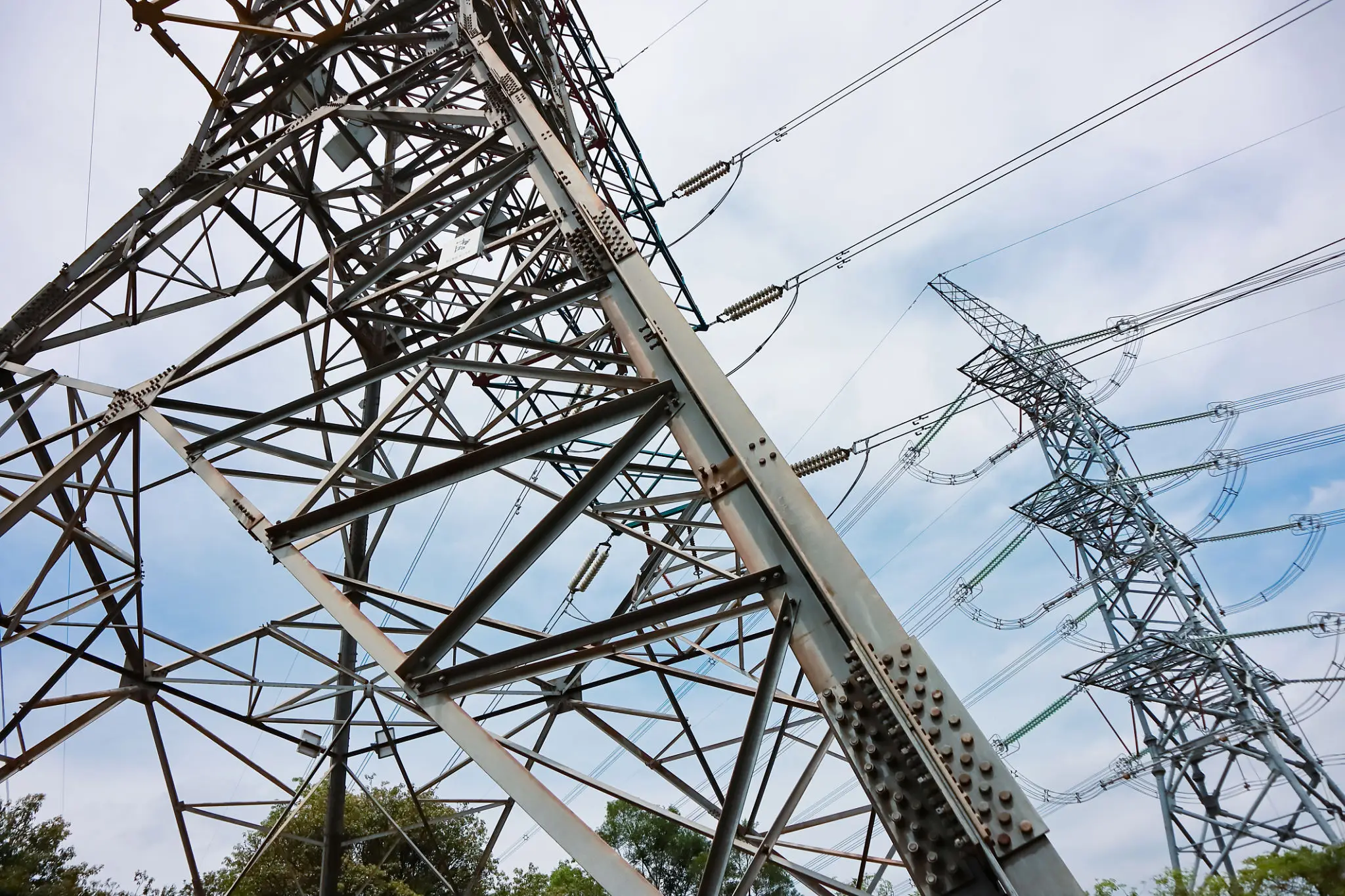 Close-up lattice transmission tower against cloudy sky