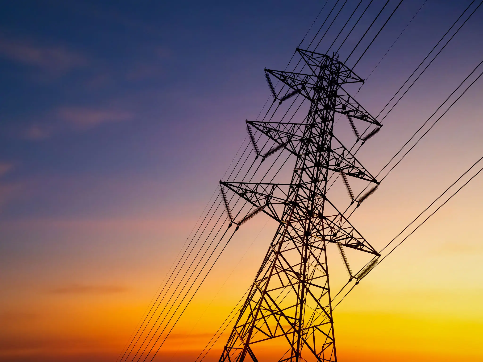 Power transmission tower silhouetted against sunset sky