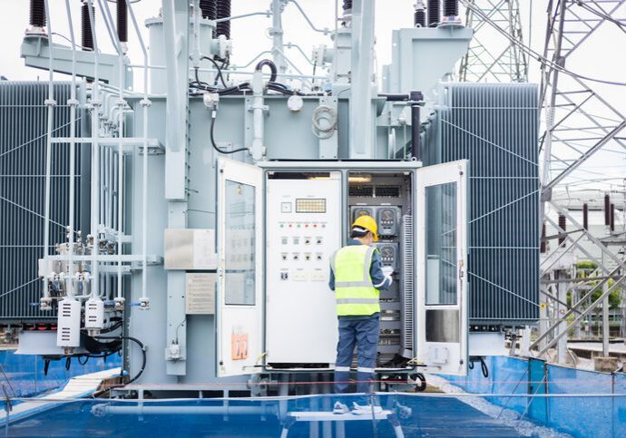 Technician inspecting electrical transformer control cabinet