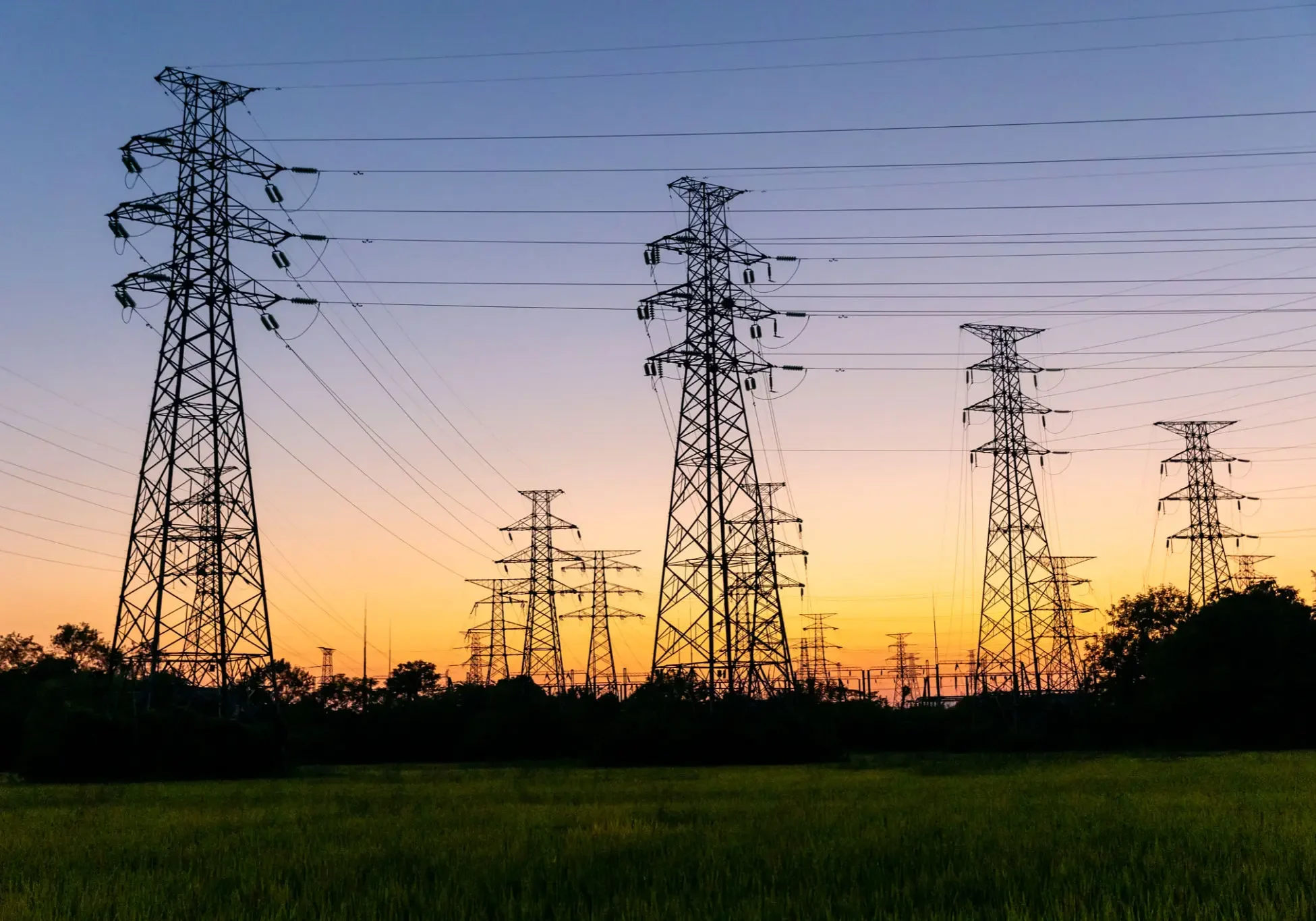 Transmission towers silhouetted against sunset sky
